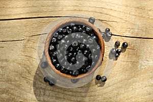 Bowl of fresh bilberries on wooden table, top view