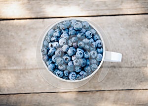 A bowl with fresh bilberry (Vaccinium myrtillus) on an old wooden bench. Fresh garden blueberries.top view