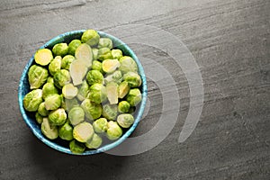 Bowl with fresh Brussels sprouts on grey table, top view.