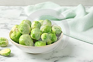 Bowl with fresh Brussels sprouts on marble table.