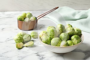 Bowl with fresh Brussels sprouts on marble table.