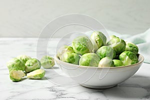 Bowl with fresh Brussels sprouts on marble table.