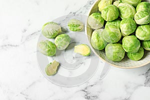 Bowl with fresh Brussels sprouts on marble table, top view.