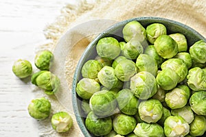 Bowl of fresh Brussels sprouts and napkin on wooden background