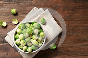 Bowl of fresh Brussels sprouts and napkin on wooden background, top view