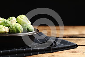 Bowl with fresh Brussels sprouts on wooden table, closeup. Space for text