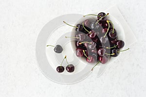 Bowl with Fresh Cherries on White Marble Board and Background