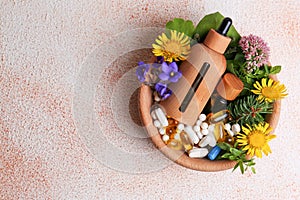 Bowl with fresh green herbs, extracts, flowers and pills on color table, top view. Space for text