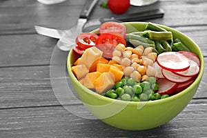 Bowl with fresh ingredients for vegetable salad on wooden table. Diet food