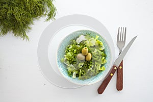 Bowl of fresh leafy green salad with olives, dill, onion and paprika