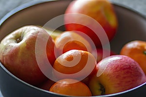 Bowl of fresh organic oranges and apples on a tabl