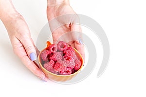 Bowl of fresh organic raspberries in hands as healthy breakfast option