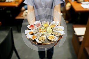 A bowl of Fresh Oyster topped with sea urchin roe uni, salmon roe ikura, wagyu beef, marinated egg yolk and spicy seafood