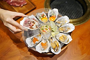 A bowl of Fresh Oyster topped with sea urchin roe uni, salmon roe ikura, wagyu beef, marinated egg yolk and spicy seafood