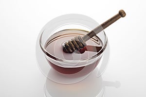 Bowl of Fresh Raw Golden Yellow Honey with a Brown Wooden Dipper