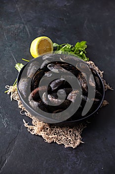 Bowl with fresh raw mussels on dark background