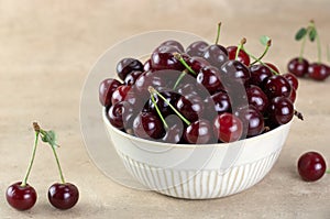 A bowl of fresh red cherries on a beige background. copy space.