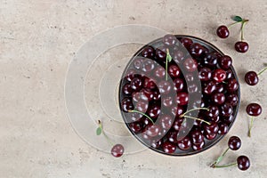 Bowl of fresh red cherries on beige background. Top view Copy space.