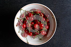 Bowl of fresh red cherries on dark background