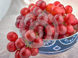 Bowl of fresh red grapes on white background