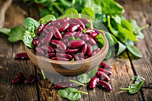 Bowl of fresh red kidney beans alongside vibrant green spinach leaves on a rustic wooden surface