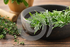 Bowl of fresh rosemary medicinal herbs. Twigs of thyme and mint on background. Healthy cooking seasonings.