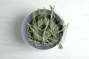 Bowl with fresh rosemary twigs on wooden table