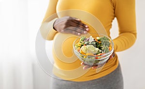 Bowl with fresh salad in pregnant black lady hands