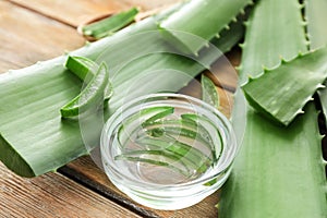 Bowl with fresh sliced aloe vera leaves and juice on wooden table