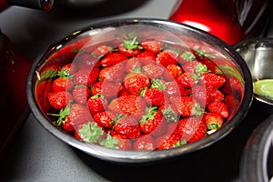 A Bowl of Fresh Strawberries soaked in water in a steel bowl