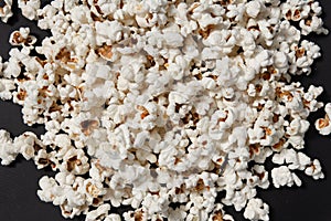 a bowl of freshly cooked popcorn on a black background, popcorn texture