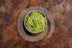 Bowl of freshly prepared fresh guacamole on a wooden background in brown tones. Healthy food rich in omega 3 fats that