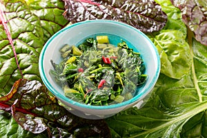 Bowl of fried chard leaves on white background. Vegetarian or vegan diet, healthy food concept