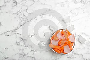 Bowl of frozen carrot and ice cubes on marble table,