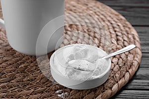 Bowl of fructose powder and cup with drink on dark wooden table, closeup