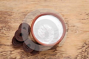 Bowl of fructose powder and fruit leather rolls on wooden table, flat lay
