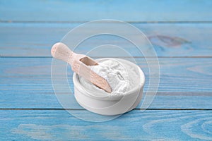 Bowl of fructose powder on light blue wooden table