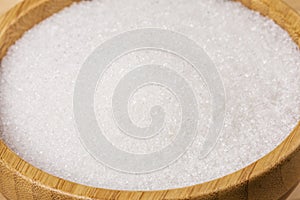 Bowl full of granulated sugar on a wooden background