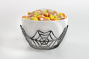 A bowl full of Halloween candy corn on a white background