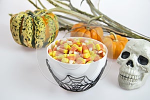 A bowl full of Halloween candy corn on a white background