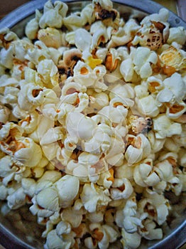 A bowl full of popcorn.popcorns are generally eaten in movies , outing or any other occasion.