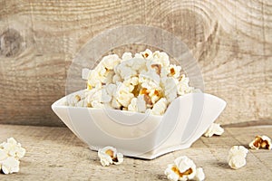 Bowl full of popcorn on wooden background