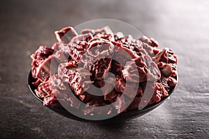 Bowl full of small cuts of beef shank on a black metallic surface