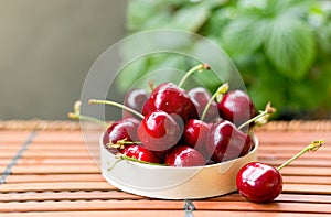 Bowl full of sweet red cherries on brown wooden background. Rustic style. Food banner, Copy space.
