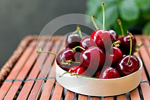 Bowl full of sweet red cherries on brown wooden background. Rustic style. Food banner, Copy space.