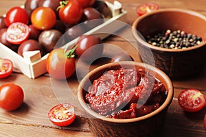 Bowl full of tomato sauce, Wooden spoon full of tomato sauce, spices, seasonings, Sliced ripe cherry tomato slices