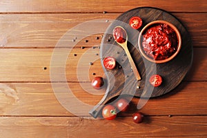 Bowl full of tomato sauce, Wooden spoon full of tomato sauce, spices, seasonings, Sliced ripe cherry tomato slices,