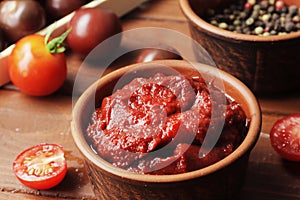 Bowl full of tomato sauce, Wooden spoon full of tomato sauce, spices, seasonings, Sliced ripe cherry tomato slices,