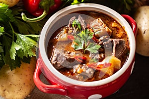 Bowl of goulash soup with meat, potatoes, chillies and parsley