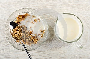 Bowl with granola and yogurt, pitcher with yogurt on wooden table. Top view